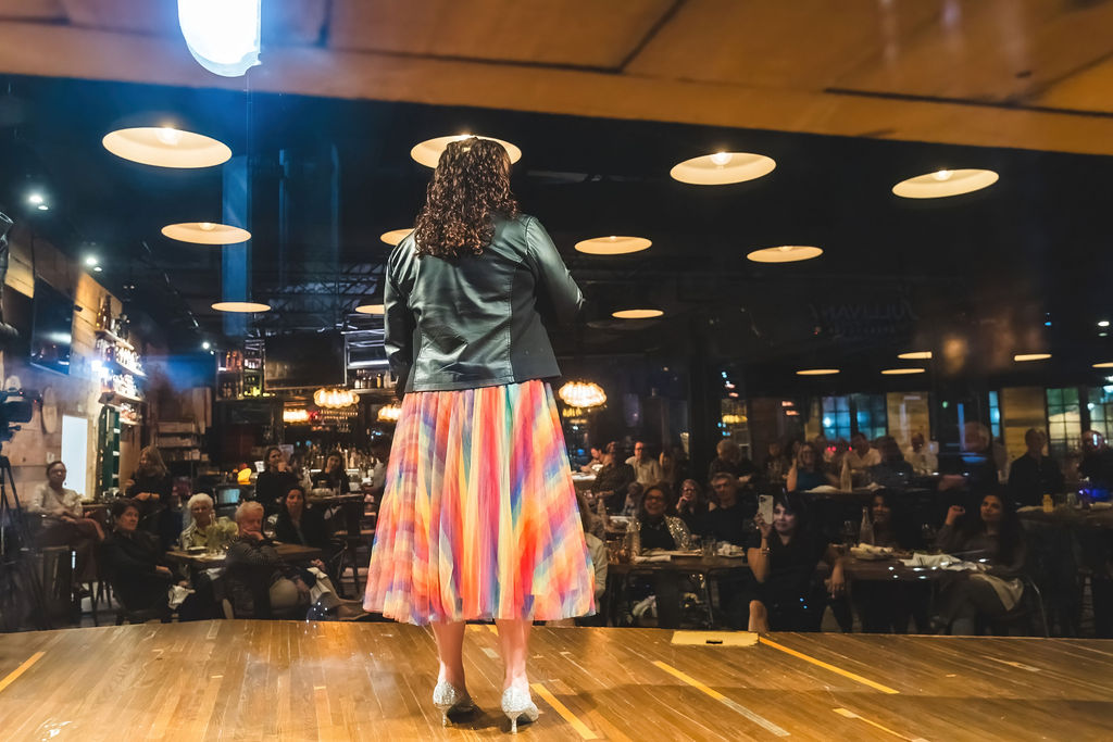 A People Tree storyteller at the microphone in front of the room